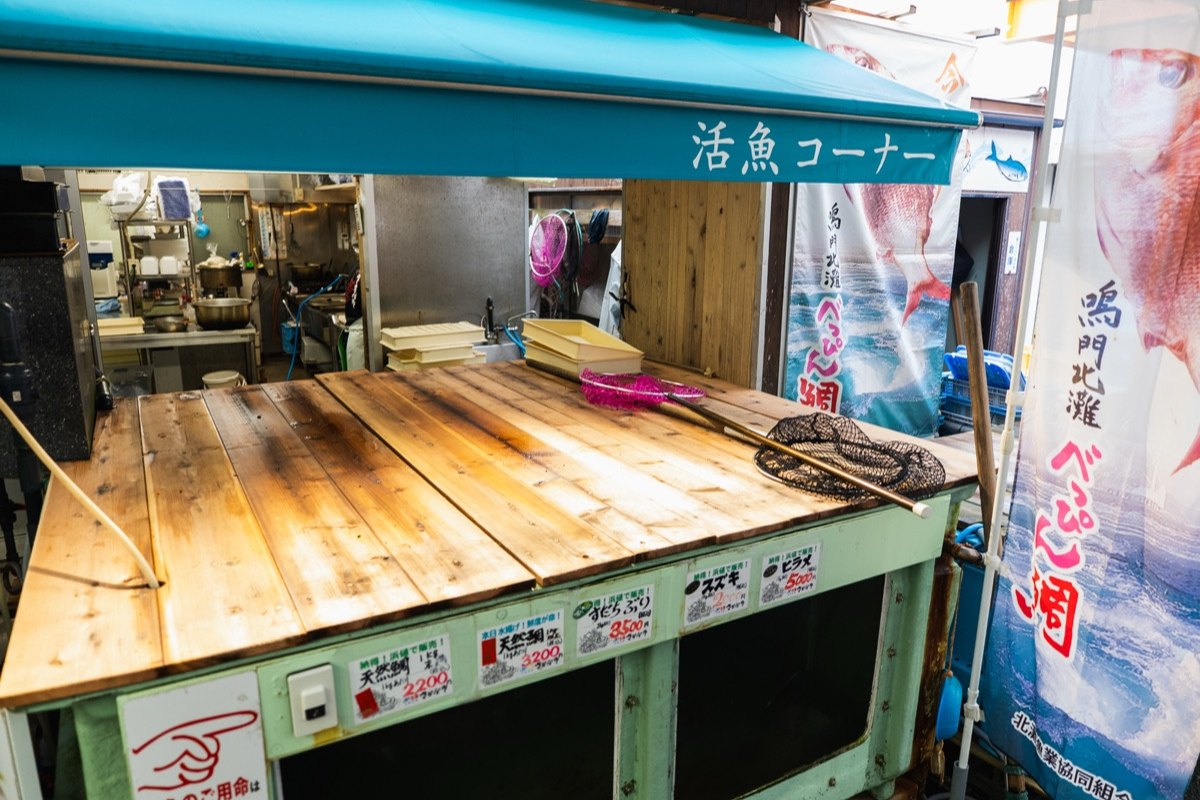 さかな市の活魚コーナー。魚種と価格の札が並ぶ