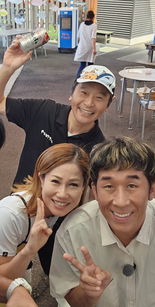 撮影の日に、さかな市で撮った記念写真。出演者のみなさんとスタッフが笑顔で並んでいる